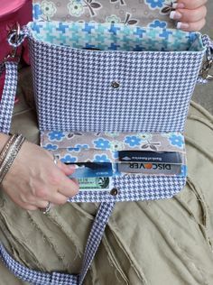 an older woman sitting on the ground holding a blue and white basket with cell phones in it