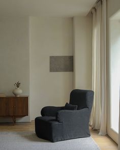 a living room with a gray chair and white walls