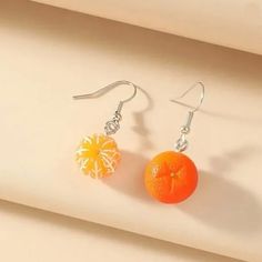 two oranges are sitting next to each other on a white surface with silver ear wires