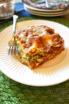 a white plate topped with lasagna covered in cheese and sauce next to a fork