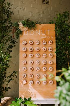 doughnuts are arranged on a wooden board in front of plants