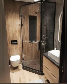 a bathroom with a toilet, sink and stand up shower in wood paneled walls