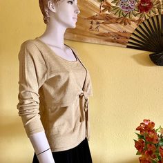 "This elegant metallic gold blouse with scoop neckline and long sleeves is vintage item from 1990s. This simple yet classic top is the perfect completion to a 1990s look, wedding, or Christmas party outfit. Made of stretchy material, knitted with shimmery gold lurex, this fabric will give you a comfort and beautiful look. The top is layered with attached short jacket, that ties on the center. - Scoop neck - Long sleeves - Front layered top attached on the sides, ties in the center - Feminine fit Elegant Gold Sweater For Winter, Elegant Gold Winter Sweater, Gold Long Sleeve Tops For Spring, Fitted Gold Tops For Winter, Fitted Gold Cardigan For Fall, Gold Cardigan For Spring Party, Gold Cardigan For Party In Spring, Gold Long Sleeve Top For Party, Gold Long Sleeve Sweater