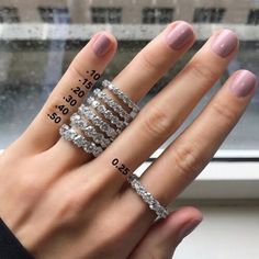 a woman's hand with five different rings on her fingers and the numbers in front of her