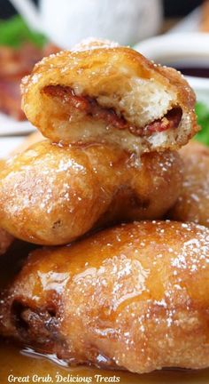 several pastries stacked on top of each other with powdered sugar and bacon in the middle