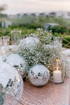 silver disco ball centerpieces with baby's breath flowers and candles on a table