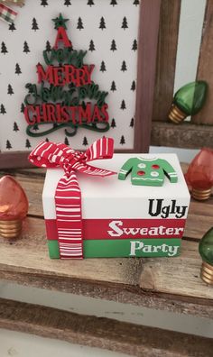 a christmas present wrapped in red and green ribbon on a wooden table next to decorations