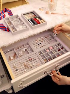 a woman is holding a drawer full of jewelry