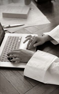 a woman using a laptop computer on top of a wooden floor in front of a desk