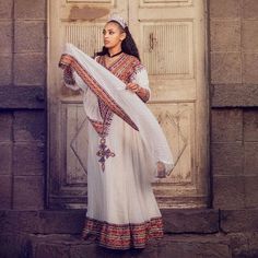 This traditional Ethiopian outfit boasts a full tilf, which is a decorative panel that runs along the bottom of the Habesha Kemis, showcasing intricate patterns and designs. The Habesha Kemis is made from Menen fabric, which is known for its high quality and durability. The Menen fabric is adorned with stunning embroidery, adding to the beauty and elegance of the outfit. The full tilf is the centerpiece of the outfit, featuring a bold and intricate design that commands attention. The colors and Navratri White Kaftan With Traditional Patterns, White Kaftan With Traditional Patterns For Navratri, Festive Habesha Kemis With Traditional Patterns, Fitted Habesha Kemis With Traditional Patterns For Ceremonies, Habesha Kemis For Eid With Traditional Patterns, Eid Habesha Kemis For Traditional Ceremonies, Habesha Kemis For Traditional Ceremonies During Eid, Fitted Habesha Kemis For Eid, Traditional White Habesha Kemis For Wedding