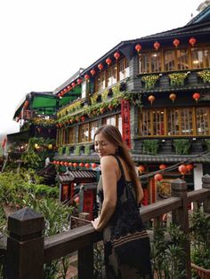 a woman standing on a wooden railing in front of a building