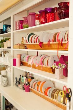 the shelves are filled with many different colored dishes and cups on them, along with other items