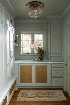 a kitchen with light green cabinets and white counter tops, along with a rug on the floor