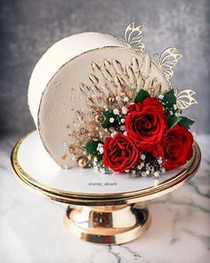 there is a white cake with red roses on the top and gold trimmings