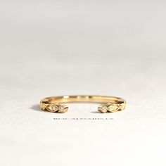 a yellow gold ring with two diamonds on the top and bottom, sitting on a white surface