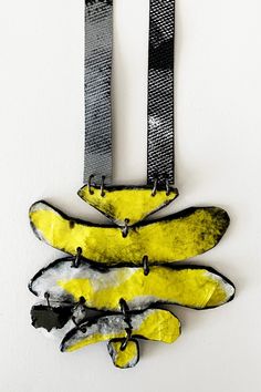 a yellow banana hanging on a wall next to a black and white belt with metal buckles