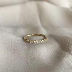 a gold wedding band with five diamonds on it's side sitting on a white cloth