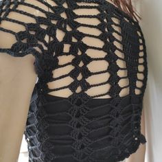 the back of a woman's black top with crochet