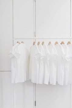 several white shirts hanging on a clothes rack