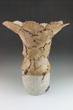 a white vase with brown leaves on it