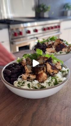 two bowls filled with food sitting on top of a wooden table next to an oven