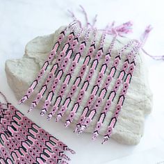 pink and black beaded tassels sitting on top of a rock next to a pair of scissors