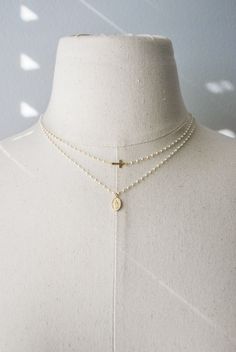 ☞ Features  ✤ Necklaces are each sold separately ✤ ✤ Tiny and dainty cross and Virgin Guadalupe white beaded necklaces. ✤ Choose between the individual necklaces or the set.  ✤ All metal parts of both necklaces are made of 18k gold vermeil material including the virgin oval pendant and cross. The tiny beads are coated with high quality white enamel that will deliver strong durability and shine. ✤ 18K Gold Vermeil - For those with an eye for striking gold, our gold jewelry uses sterling silver as Minimalist White Crucifix Jewelry, Spiritual Cross-shaped Pearl Chain Jewelry, Cross Shaped Beaded Chain Necklace Gift, Cross Shaped Beaded Chain Necklace For Gift, Cross Shaped Beaded Chain Necklace As Gift, Cross-shaped Beaded Chain Necklace For Gift, White Spiritual Crucifix Necklace, White Crucifix Spiritual Necklace, Delicate Everyday Cross Necklace