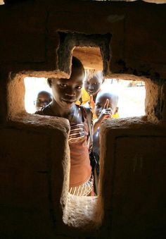 a group of young children standing inside of a brick building with one child looking at the camera