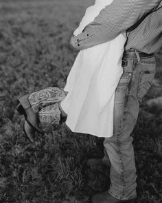 black and white photograph of a couple embracing each other in an open field with grass