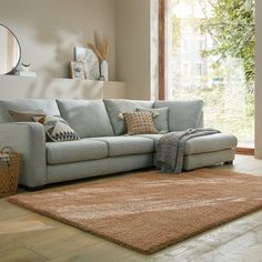 a living room scene with focus on the corner sofa and rug in the foreground