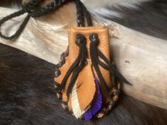 a brown leather pouch with purple and white feathers