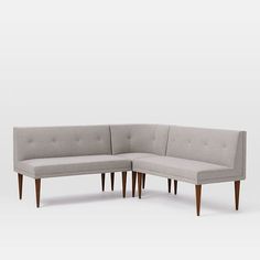 a gray sectional couch with wooden legs on a white background