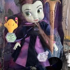 the doll is wearing a purple dress and holding a golden sception in her hand