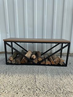 a table made out of wood and metal with some logs stacked on top of it