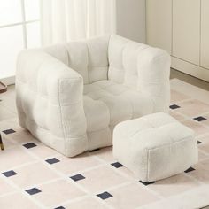 a white chair and footstool in a room with a rug on the floor