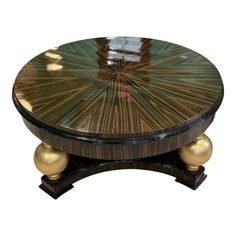 a wooden table with two gold balls on it's legs and a circular top