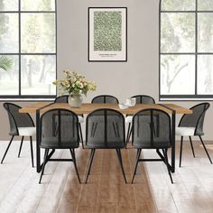 a dining room table with chairs and a vase filled with flowers on top of it