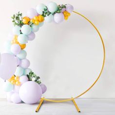 the balloon arch is decorated with pastel balloons and greenery