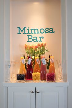 the minimosa bar is set up on top of a white cabinet with flowers in vases