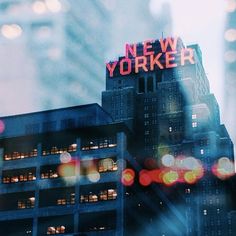 the words new york are lit up on top of a tall building in the city