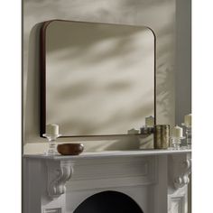 a fireplace with a mirror on top of it next to a candle holder and candles