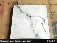 a white marble tile on top of a wooden floor next to a wall with graffiti