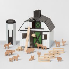 a toy farm with wooden animals and a barn