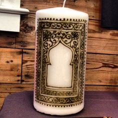 a lit candle sitting on top of a table next to a piece of paper with an intricate design