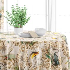 a table with a bowl and plate on it next to a plant in a vase