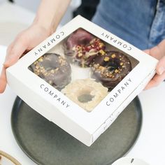 a person holding up a box of doughnuts