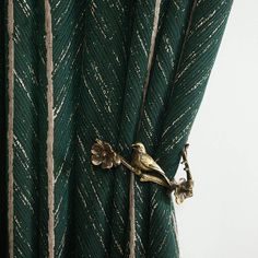 a bird is perched on top of the green curtain in front of it's window