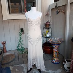 a white dress is on display in front of a house with other items around it