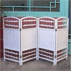 a white room divider sitting in front of a blue door with red and white designs on it