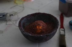 a bowl that has some kind of substance in it next to paintbrushes and glue